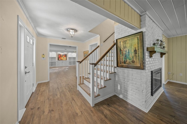 entryway with ornamental molding, a brick fireplace, and dark hardwood / wood-style flooring