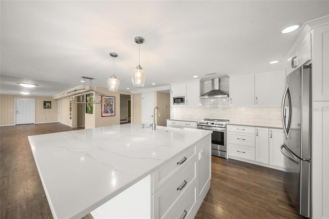 kitchen with wall chimney exhaust hood, appliances with stainless steel finishes, and a large island with sink