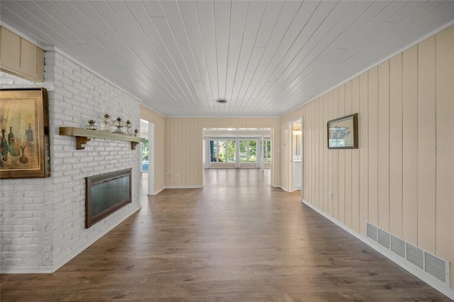 unfurnished living room featuring wood ceiling, wooden walls, hardwood / wood-style floors, and a brick fireplace