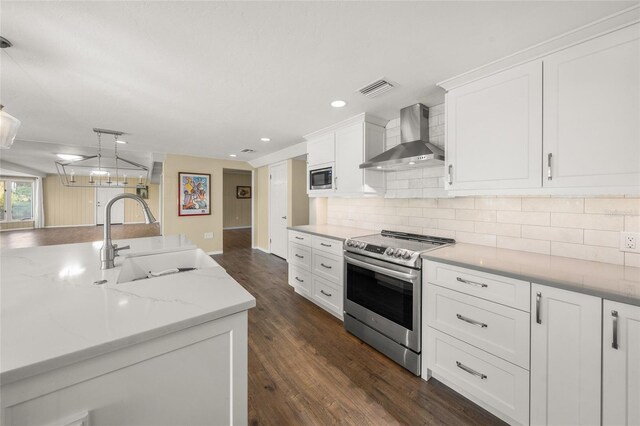 kitchen featuring appliances with stainless steel finishes, dark wood-type flooring, pendant lighting, sink, and wall chimney range hood