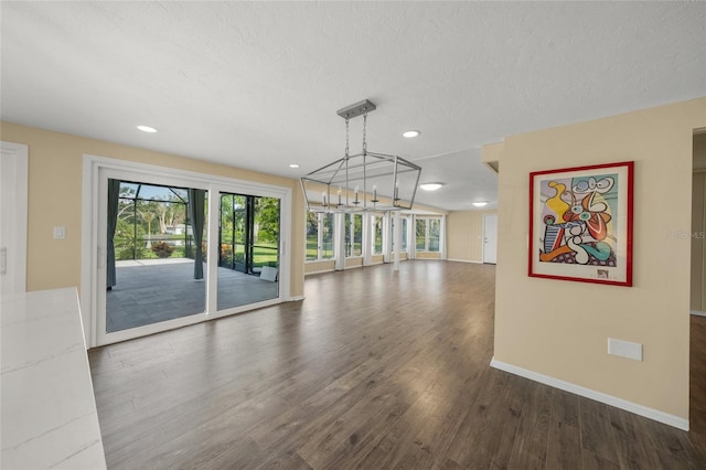 empty room with a textured ceiling, a chandelier, and dark wood-type flooring