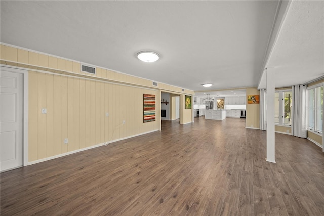 unfurnished living room featuring wooden walls and dark hardwood / wood-style floors