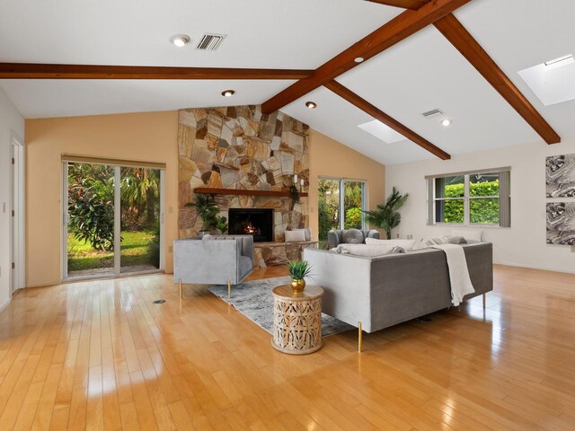 living room featuring light hardwood / wood-style flooring, lofted ceiling with skylight, a wealth of natural light, and a fireplace