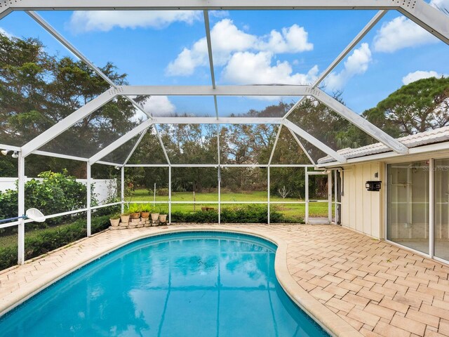 view of pool with glass enclosure and a patio area