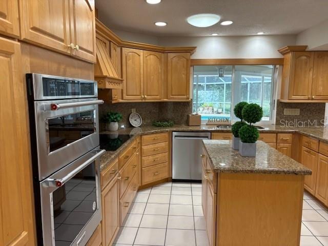 kitchen featuring backsplash, stone countertops, appliances with stainless steel finishes, and a kitchen island