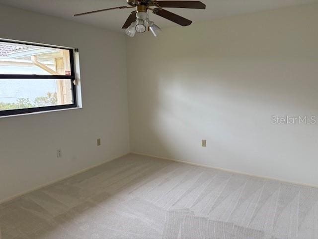 carpeted spare room featuring ceiling fan