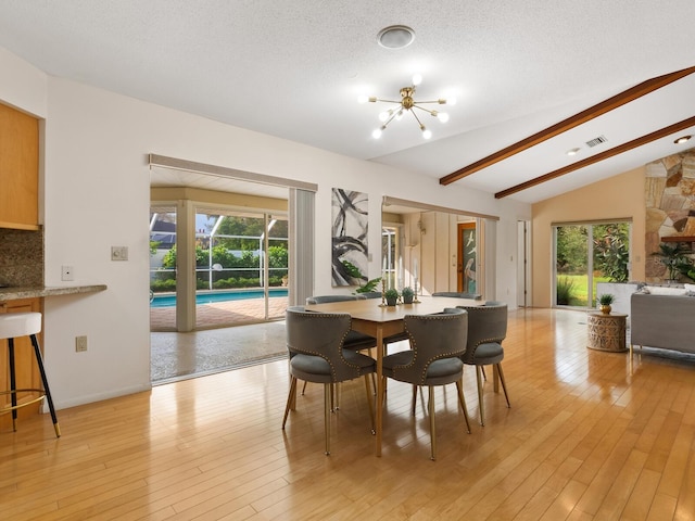 dining space with a textured ceiling, plenty of natural light, lofted ceiling with beams, and light hardwood / wood-style floors