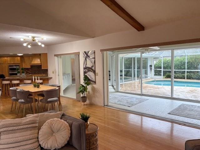 living room featuring light wood-type flooring and lofted ceiling with beams