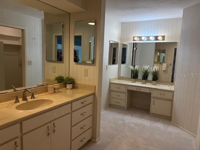 bathroom featuring wooden walls, a textured ceiling, and vanity