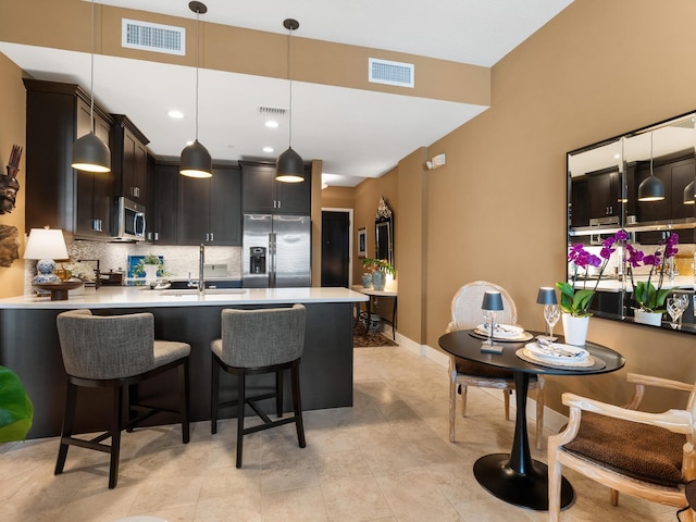 kitchen with dark brown cabinetry, stainless steel appliances, sink, and hanging light fixtures