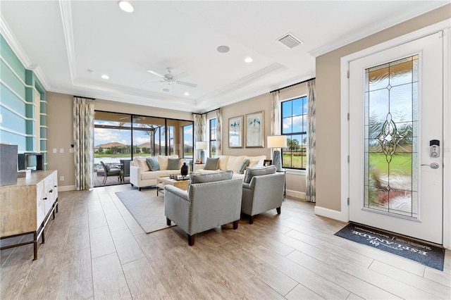 living room featuring ceiling fan, a raised ceiling, crown molding, and light hardwood / wood-style flooring