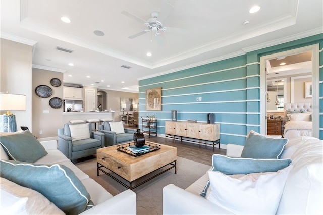 living room featuring crown molding, a raised ceiling, wood-type flooring, and ceiling fan