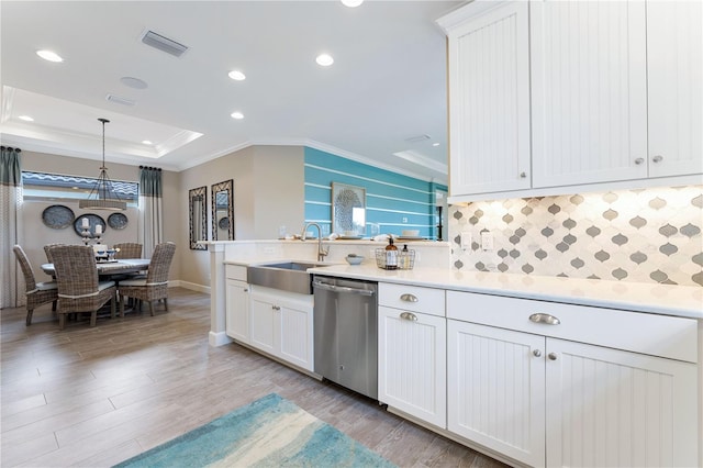 kitchen with a raised ceiling, decorative light fixtures, light hardwood / wood-style flooring, stainless steel dishwasher, and sink