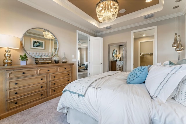 carpeted bedroom featuring ornamental molding, an inviting chandelier, a closet, a tray ceiling, and a walk in closet