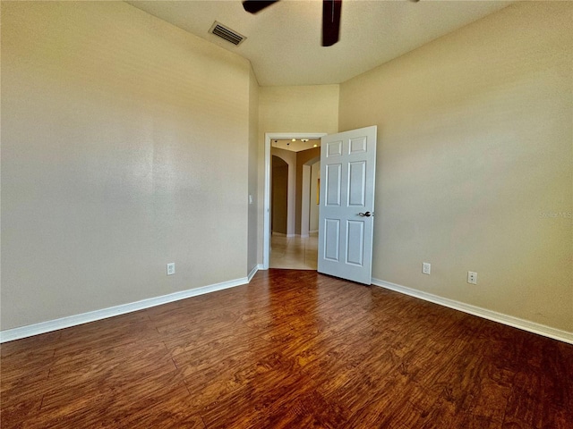 empty room featuring hardwood / wood-style floors, a towering ceiling, and ceiling fan