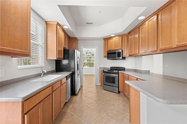 kitchen featuring light tile patterned floors, stainless steel appliances, sink, a raised ceiling, and kitchen peninsula