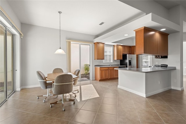 kitchen featuring light tile patterned floors, decorative light fixtures, kitchen peninsula, sink, and stainless steel fridge with ice dispenser