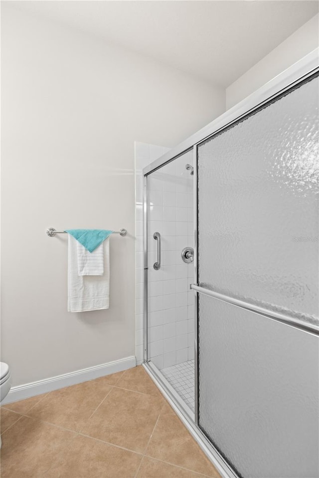 bathroom featuring a shower with shower door, toilet, and tile patterned floors