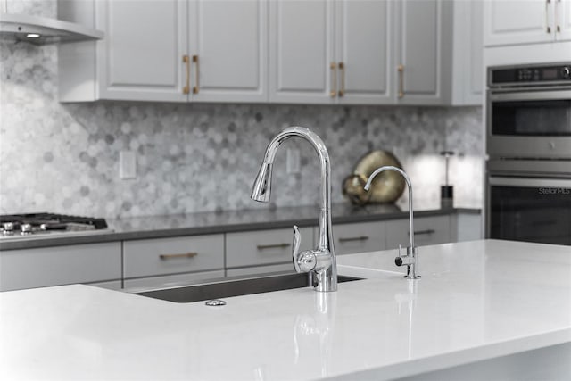 kitchen with white cabinets, sink, tasteful backsplash, ventilation hood, and appliances with stainless steel finishes