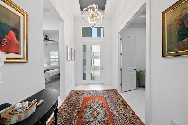 foyer with ceiling fan with notable chandelier and ornamental molding