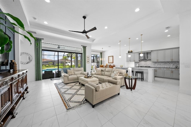 living room featuring ceiling fan and a tray ceiling