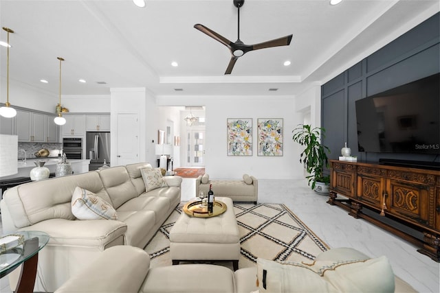 living room featuring a tray ceiling, ornamental molding, and ceiling fan