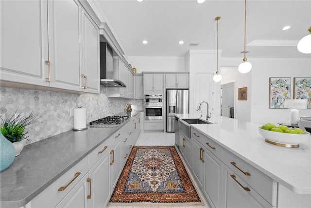 kitchen with appliances with stainless steel finishes, decorative light fixtures, sink, wall chimney range hood, and a spacious island