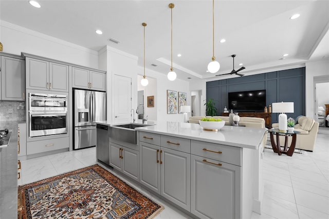 kitchen with ceiling fan, an island with sink, sink, gray cabinetry, and stainless steel appliances