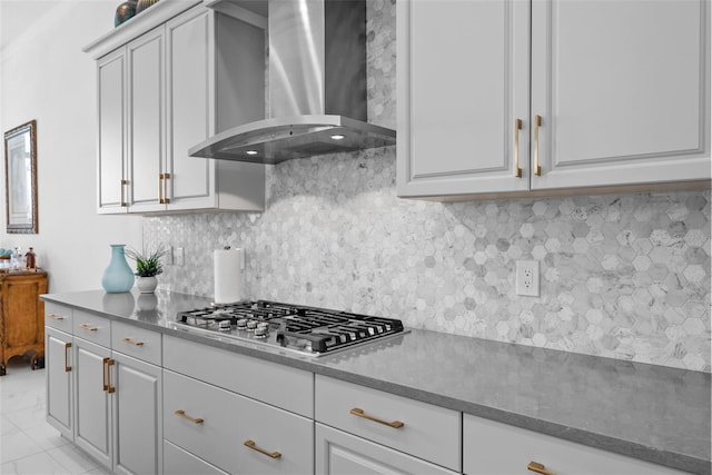 kitchen with decorative backsplash, dark stone countertops, stainless steel gas cooktop, and wall chimney range hood