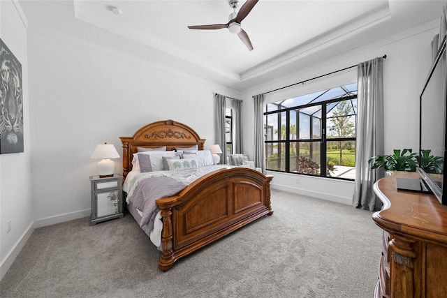 carpeted bedroom featuring ornamental molding, a tray ceiling, and ceiling fan