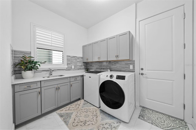 washroom with cabinets, washing machine and clothes dryer, and sink