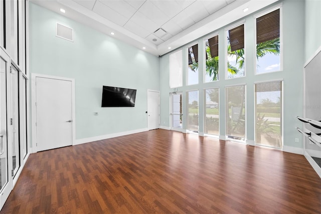 unfurnished living room with dark wood-type flooring and a high ceiling