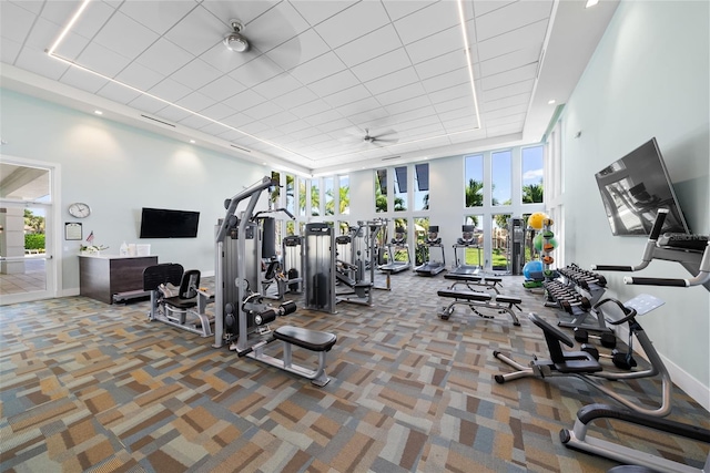 gym featuring carpet flooring, a towering ceiling, and ceiling fan