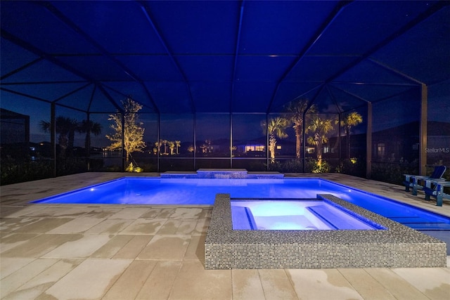 pool at twilight with a patio and an in ground hot tub