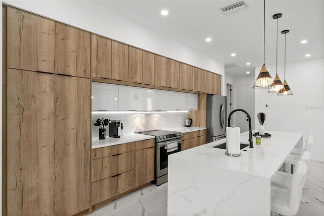 kitchen featuring hanging light fixtures, light stone countertops, stainless steel appliances, sink, and an island with sink