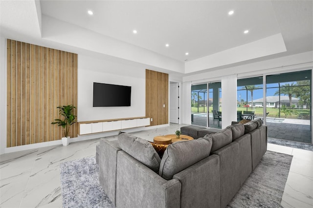 living room with a tray ceiling and wooden walls