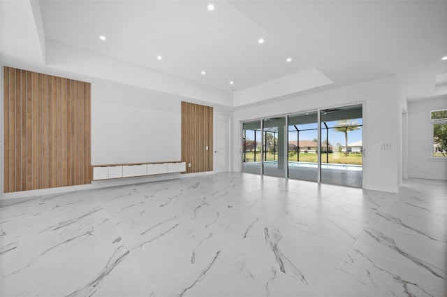 unfurnished room with wood walls and a tray ceiling