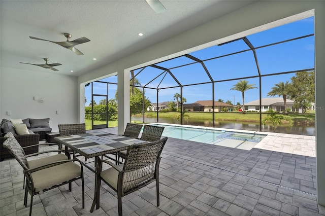 view of patio featuring a water view, ceiling fan, and glass enclosure