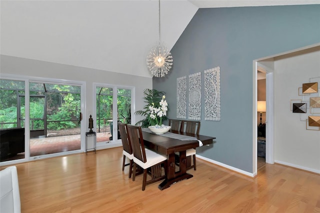 dining room with a chandelier, high vaulted ceiling, and light wood-type flooring