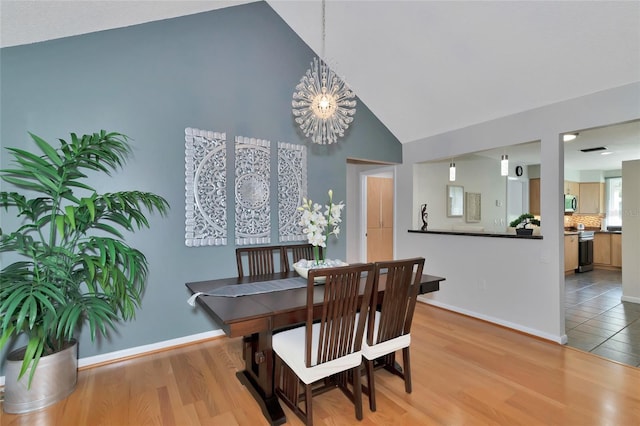 dining space with vaulted ceiling, a chandelier, and hardwood / wood-style floors