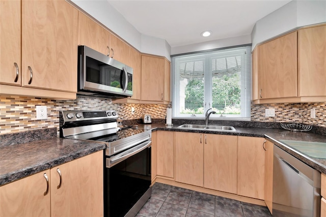 kitchen with light brown cabinetry, sink, appliances with stainless steel finishes, dark tile patterned flooring, and decorative backsplash