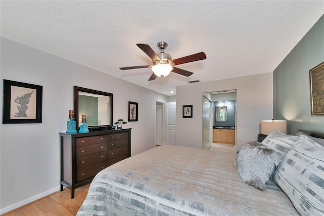 bedroom with connected bathroom, a textured ceiling, ceiling fan, and light hardwood / wood-style floors