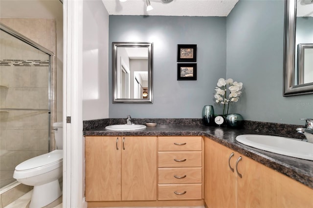 bathroom with walk in shower, vanity, toilet, and a textured ceiling