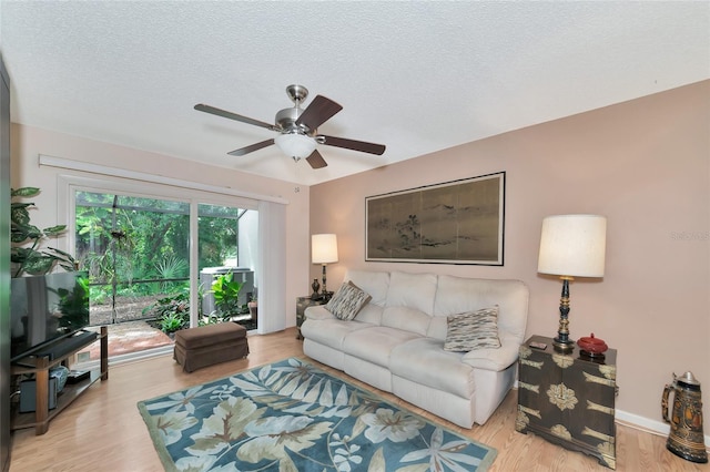 living room with ceiling fan, a textured ceiling, and light wood-type flooring