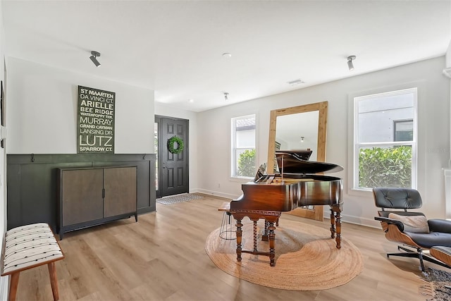 living area featuring light wood-style flooring, visible vents, baseboards, and a wealth of natural light