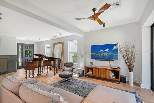 living room featuring beam ceiling, visible vents, and wood finished floors