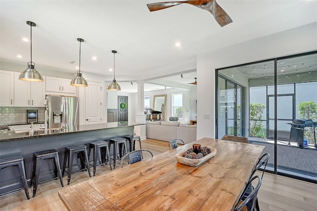 dining space with light wood-style floors, decorative columns, a ceiling fan, and recessed lighting