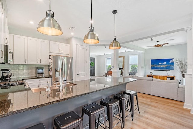 kitchen with visible vents, appliances with stainless steel finishes, dark stone countertops, a peninsula, and light wood-style floors