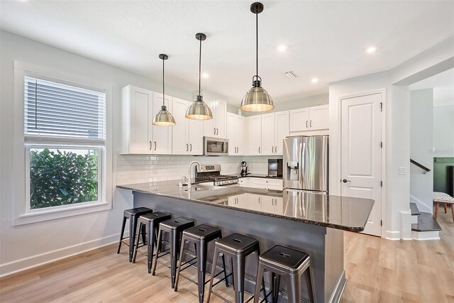 kitchen featuring visible vents, decorative backsplash, a kitchen breakfast bar, a peninsula, and stainless steel appliances