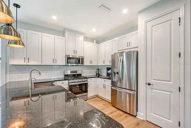 kitchen featuring visible vents, decorative backsplash, light wood-style flooring, stainless steel appliances, and a sink